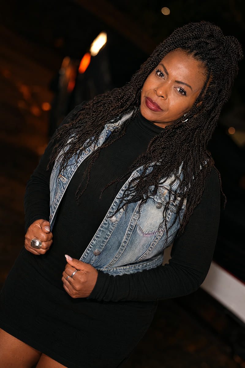 Iyono (vocals) in a denim jacket, leaning against the truck.